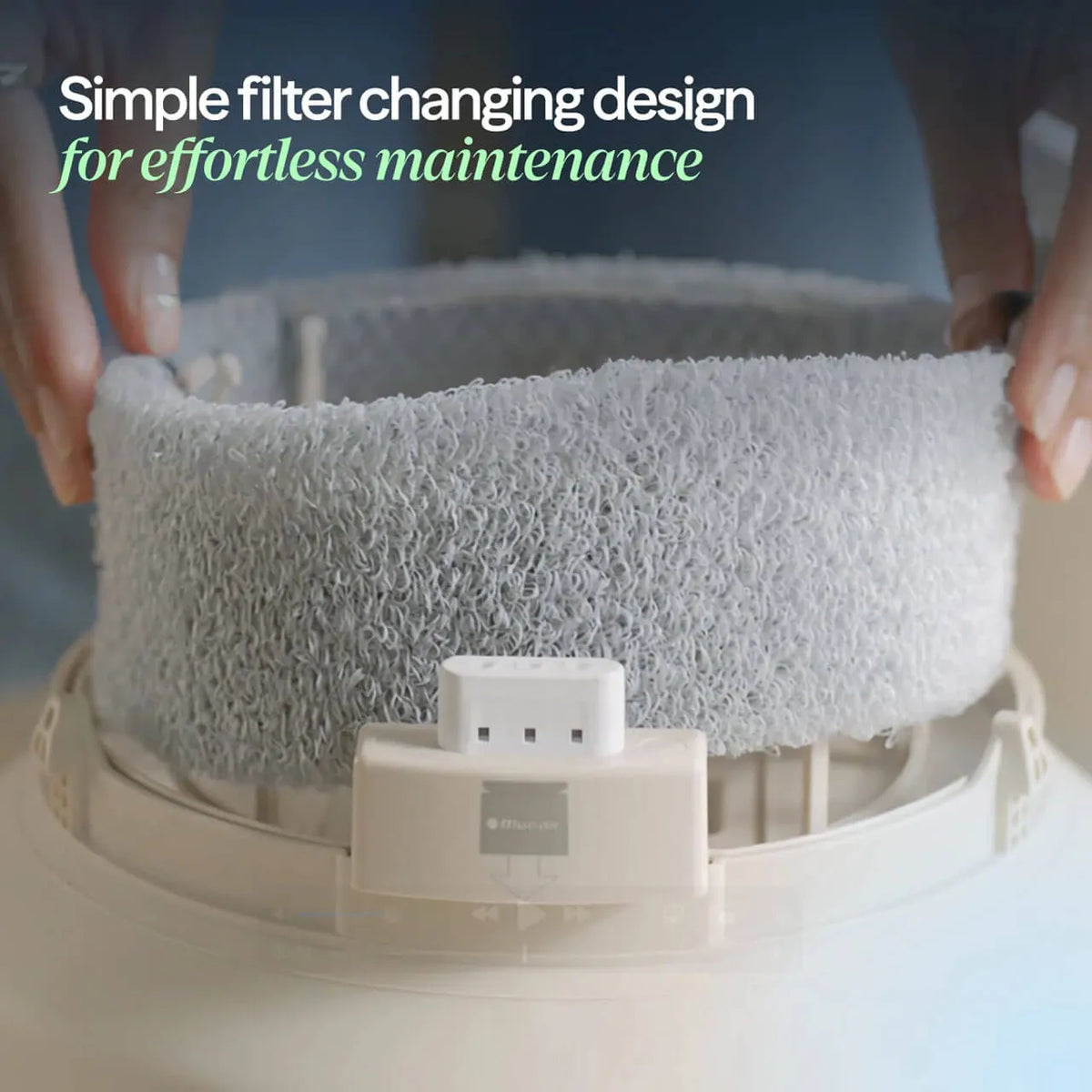 Hände setzen den runden Blueair DreamWell H38i Wick-Ersatzfilter in das Gerät ein, Grafiktext „Simple filter changing design“