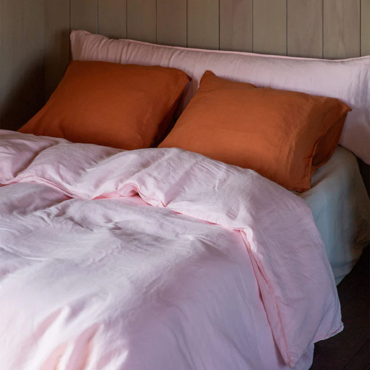 Suite702 bedMATE Leinen-Kissenbezüge in Terra auf Bett mit rosa Bettwäsche und Kopfteil