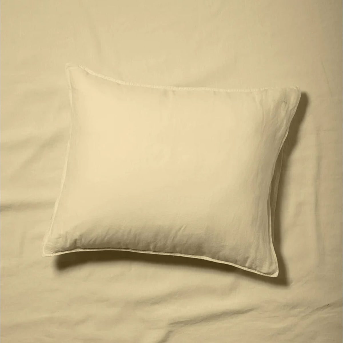 Suite702 Leinen-Mix Kissenbezug in Creamy Yellow, liegend auf Bettwäsche, Draufsicht