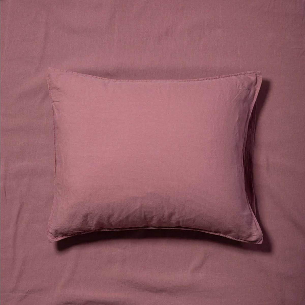 Suite702 Leinen-Mix Kissenbezug in Mauve Rose, liegend auf gleichfarbigem Bettlaken, Draufsicht