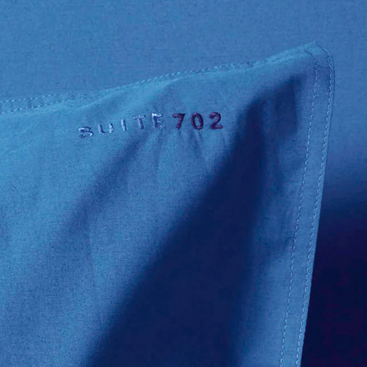 Nahaufnahme der Eckennaht des Suite702 Perkal Kissenbezugs in Cobalt Blue mit Stickschriftzug „Suite702 702“