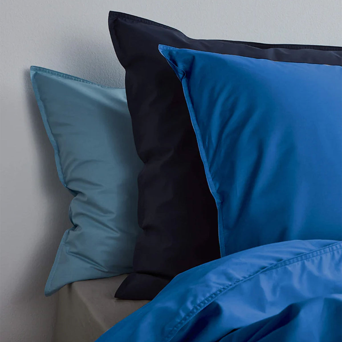 Suite702 Perkal Kissenbezüge aus Bio-Baumwolle in Hellblau, Dunkelblau und Cobalt Blue, aufgestellt auf dem Bett
