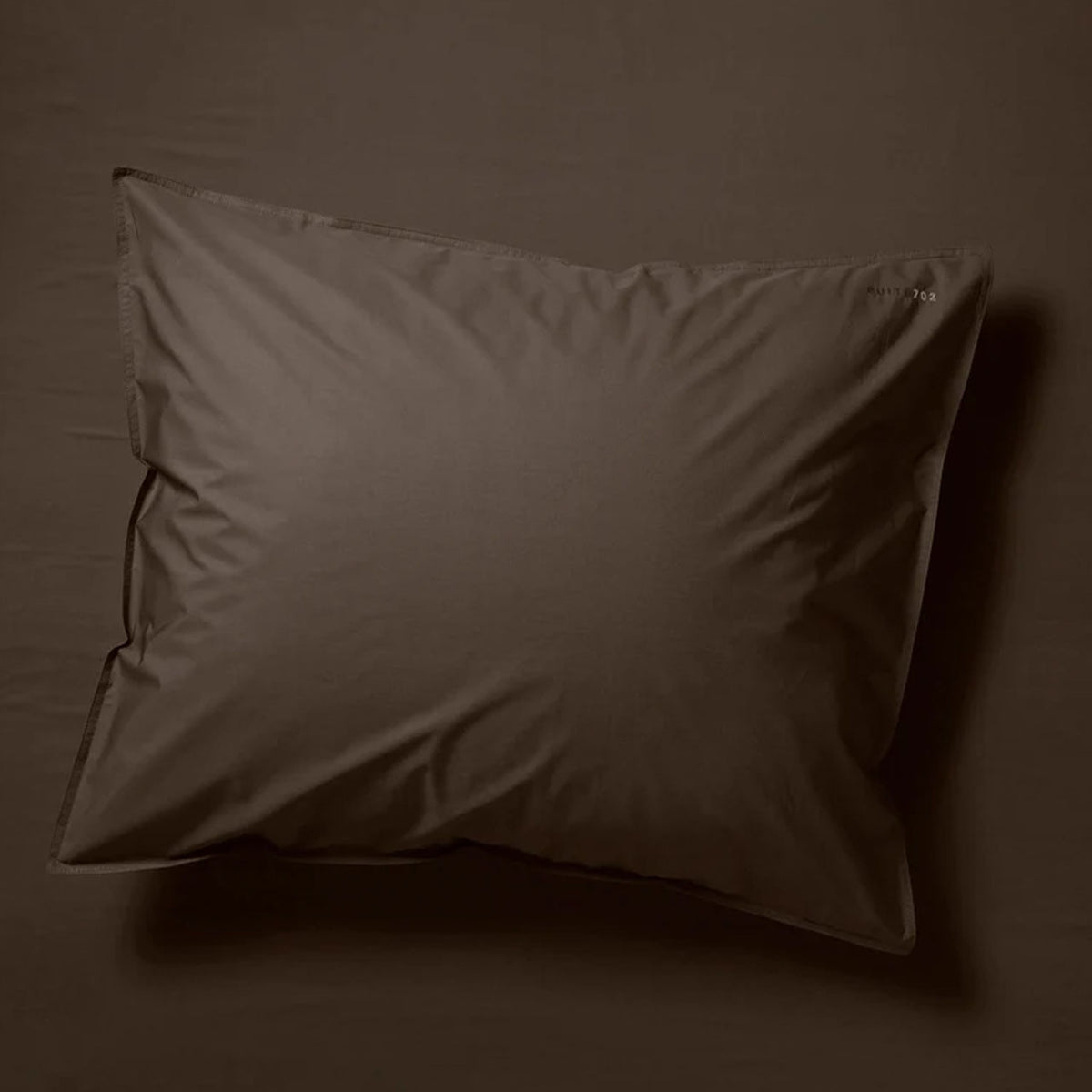 Suite702 Perkal Kissenbezug aus Bio-Baumwolle in Coffee Brown, Gesamtansicht auf dunklem Untergrund