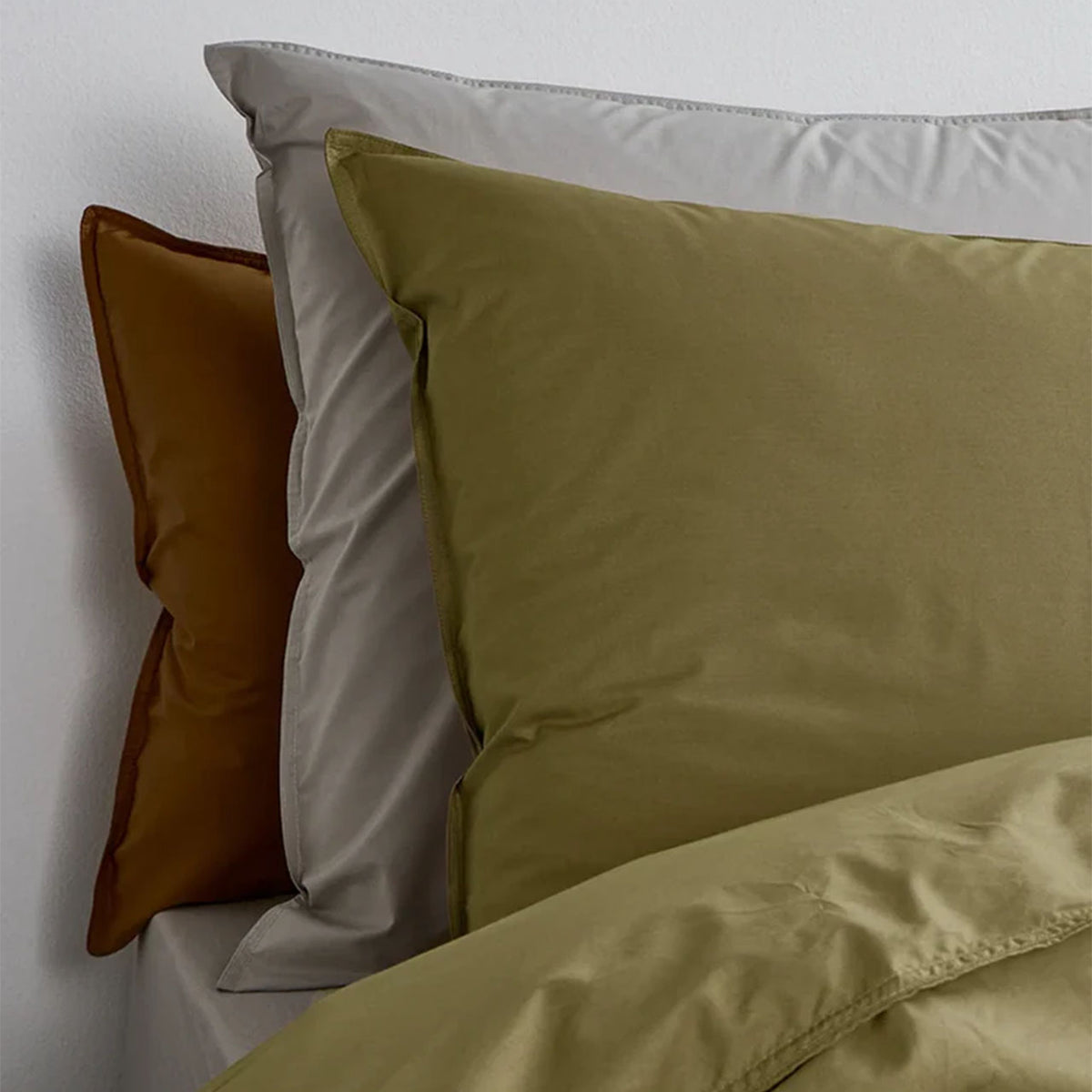 Suite702 Perkal Kissenbezüge aus Bio-Baumwolle in Olive Green, Grau und Camel im Bett gestapelt