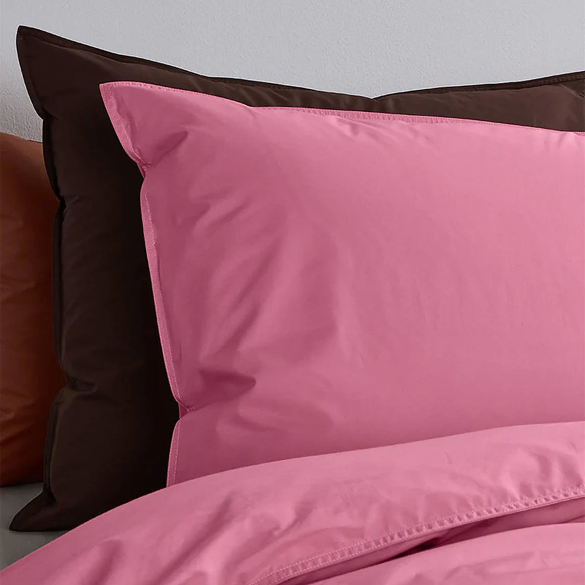 Suite702 Perkal Kissenbezug aus Bio-Baumwolle in Pink, Nahaufnahme auf braunem Kissen im Bett