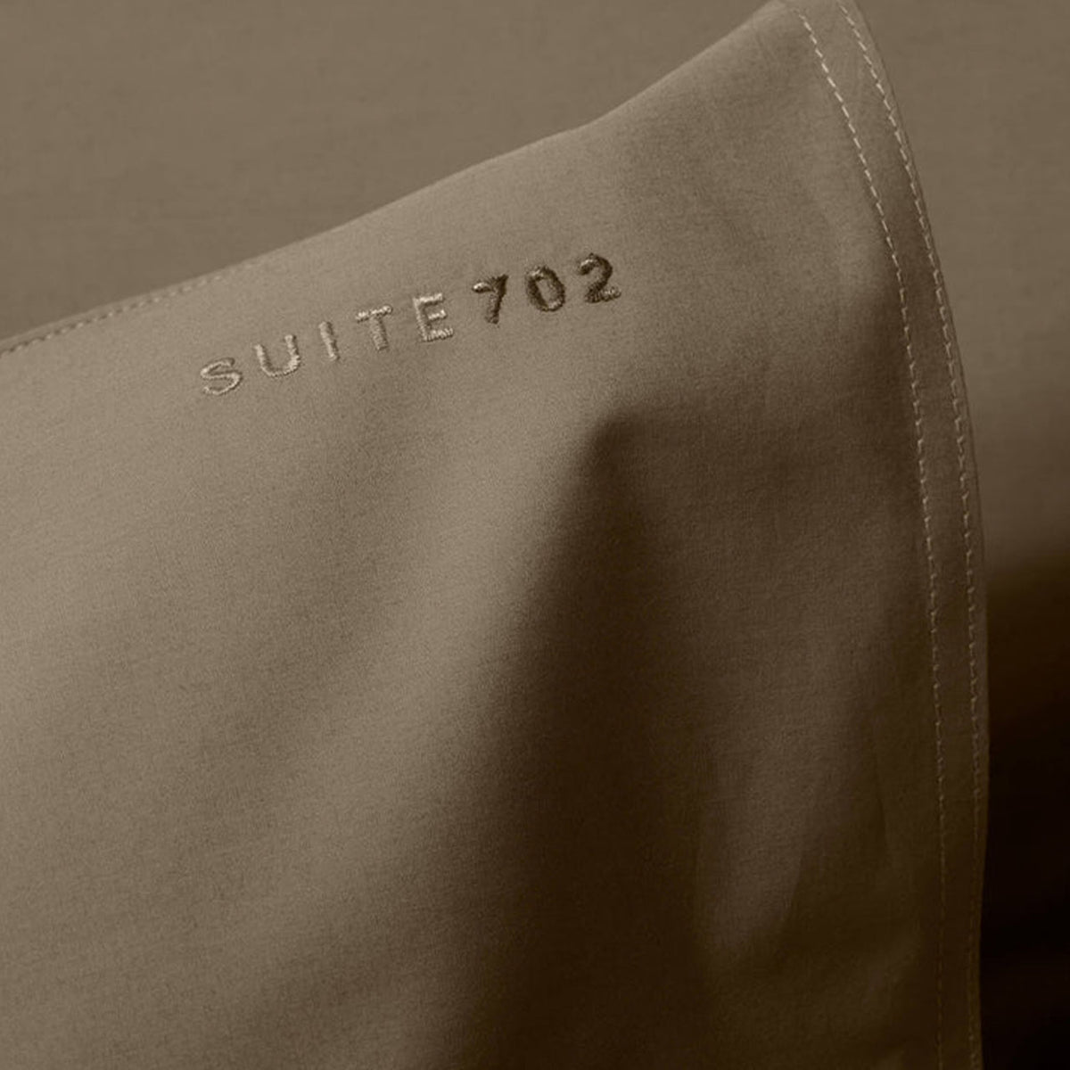 Nahaufnahme des gestickten „Suite702“-Schriftzugs auf Perkal-Kissenbezug in Smokey