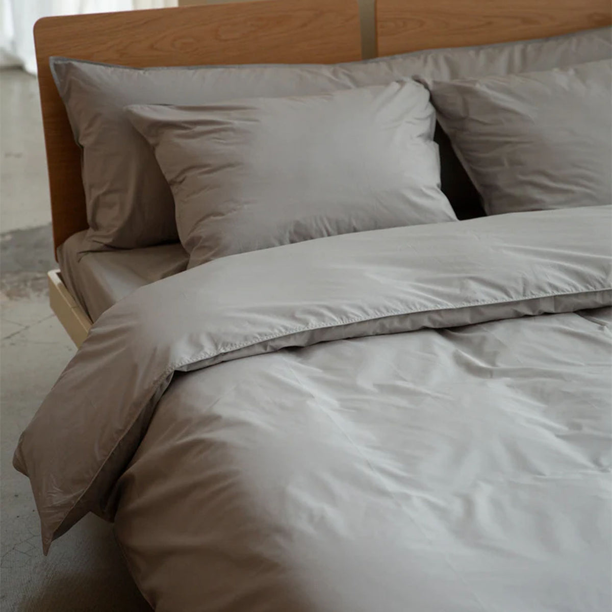 Bett mit Suite702 Perkal-Bettwäsche in Urban Grey, Kissenbezüge und Bettdecke am Holzbett